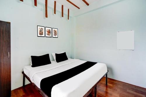 a white room with a bed with black and white sheets at HOTEL O MID STAR in Sakardarā