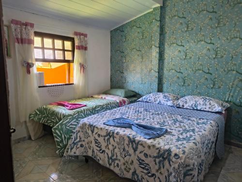 een slaapkamer met twee bedden en een raam bij Chalé da Elba 01 Ilhabela in Ilhabela
