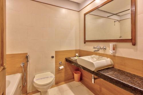 Un baño con lavabo, inodoro y espejo. en Shingar Regency, en Manali