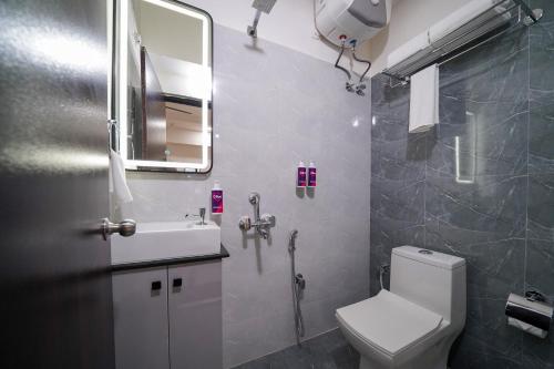 Un baño con inodoro, lavabo y espejo. en Olive Hotel Hitec City by Embassy Group, en Hyderabad