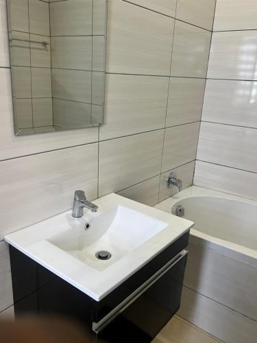 a bathroom with a white sink and a bath tub at Lekki holiday shortlet in Lekki