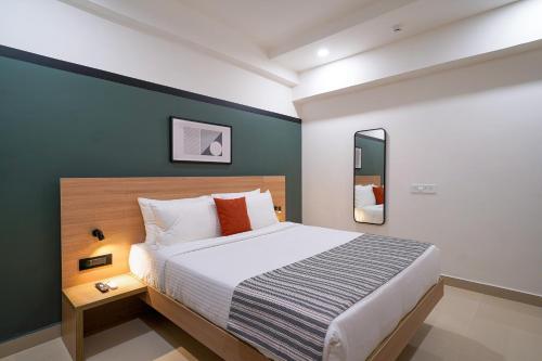 Un dormitorio con una cama y una pared verde. en Olive Hotel Hitec City by Embassy Group, en Hyderabad