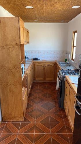 a kitchen with wooden cabinets and a tile floor at El Fortín de los Choros, un descanso para la familia in Los Choros