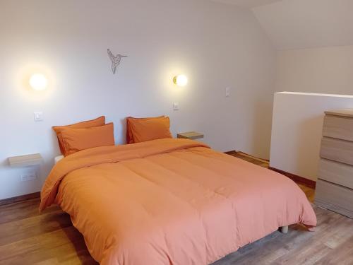 索姆勒兹Au nid du colibri的一间卧室配有一张带橙色床罩的床