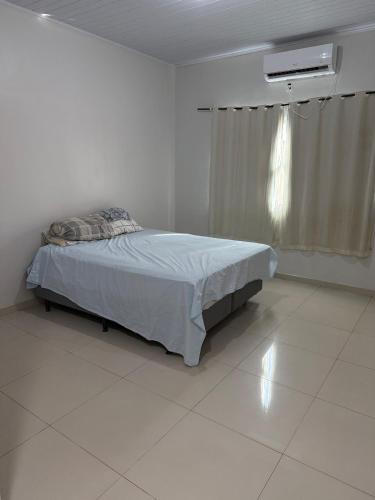 um quarto com uma cama em um quarto branco em Casa completa com dois quartos e uma suíte master, localizada no bairro Alphaville Fazendinha em Macapá