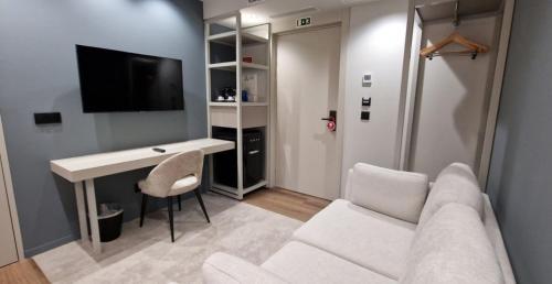 a living room with a white couch and a desk at Bom Sucesso Hotel by gaiarooms in Porto