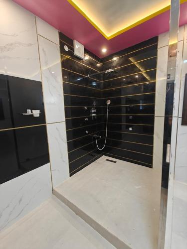 a bathroom with a shower with black and white tiles at Malathi Residency in Arumuganeri