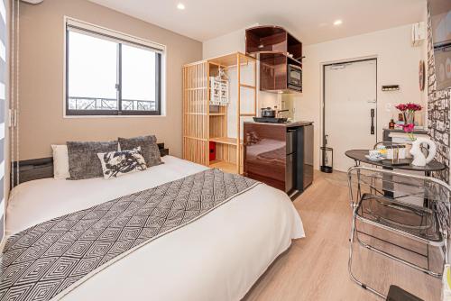 a bedroom with a bed and a desk and a window at Mi-HOTEL SHIMOKITAZAWA in Tokyo