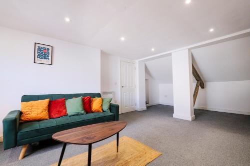a living room with a green couch with colorful pillows at Spacious 2 Bedroom Apartment, Free Parking, WiFi in Gloucester