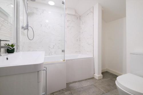 a white bathroom with a tub and a sink at Spacious 2 Bedroom Apartment, Free Parking, WiFi in Gloucester