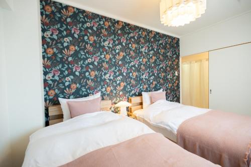 two beds in a room with a floral wallpaper at 海が見える隠れ家 -Tsukushi瀬戸内- in Takamatsu