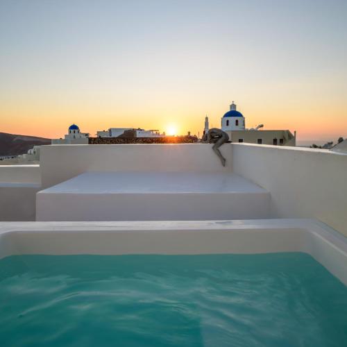a person is sitting on the edge of a swimming pool at Oia Treasures Art Suites in Oia