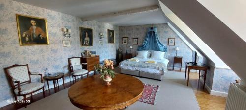 ein Schlafzimmer mit einem Bett und einem Tisch und Stühlen in der Unterkunft Le Château D'Osthoffen in Osthoffen