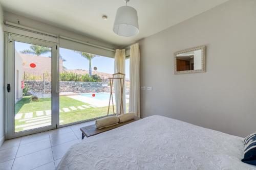 een slaapkamer met een bed en uitzicht op een zwembad bij Premium House with Private Heated Pool and Bbq in La Playa de Arguineguín