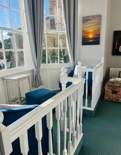 una stanza con una scala con sedie blu e finestre di The Ilchester Arms ad Abbotsbury