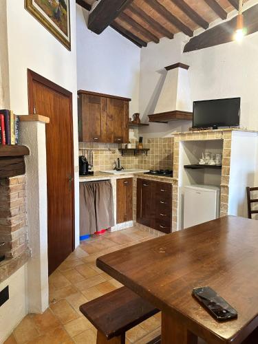 a kitchen with a wooden table and a white refrigerator at Il Borgo Del Lupo Relax Family Apartments in Tuscany with Restaurant & Swimming Pool in Sarteano