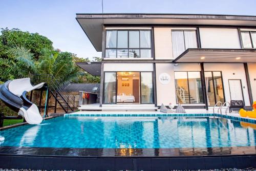a swimming pool with a slide in front of a house at Emery Pool Villa Pattaya in Ban Huai Yai