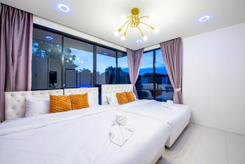 ein Schlafzimmer mit zwei weißen Betten und einem Fenster in der Unterkunft Emery Pool Villa Pattaya in Ban Huai Yai