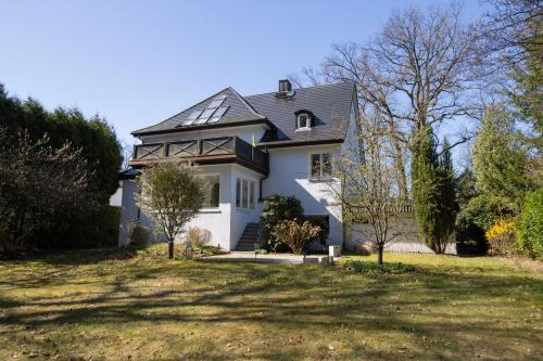 ein weißes Haus mit einem schwarzen Dach in der Unterkunft Gästezimmer Volksdorf in Hamburg