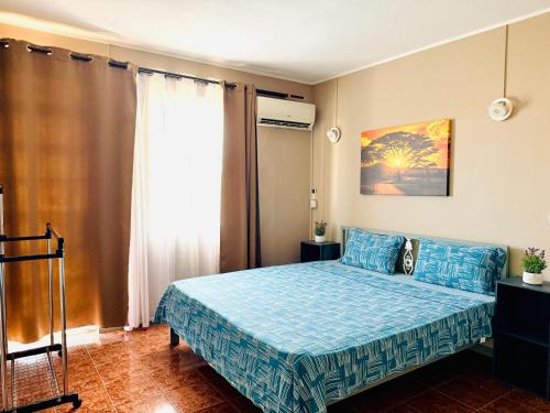 a bedroom with a blue bed and a window at Devika villa in Triolet