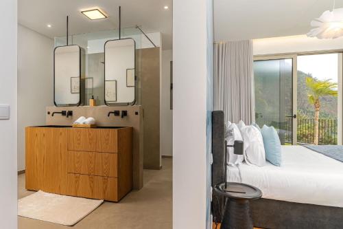 a bedroom with a bed and a mirror at Elysium São Vicente - Designer Villa with Ocean View, Heated Pool, Jacuzzi & Sauna in São Vicente