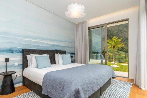 a bedroom with a bed and a large window at Elysium São Vicente - Designer Villa with Ocean View, Heated Pool, Jacuzzi & Sauna in São Vicente