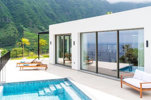 a house with a pool and a view of the mountains at Elysium São Vicente - Designer Villa with Ocean View, Heated Pool, Jacuzzi & Sauna in São Vicente