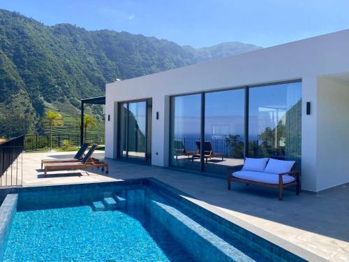 a villa with a swimming pool and a house at Elysium São Vicente - Designer Villa with Ocean View, Heated Pool, Jacuzzi & Sauna in São Vicente