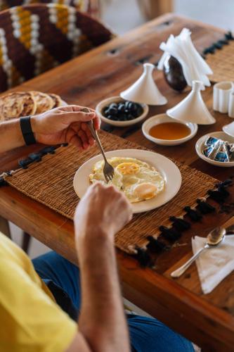 a person sitting at a table with a plate of food at Ô TALIA Hôtel and SPA in Nungwi