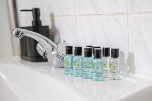 a bathroom sink with three bottles of soap and a faucet at Spacious 4 Bed 2 Bath House in Beoley