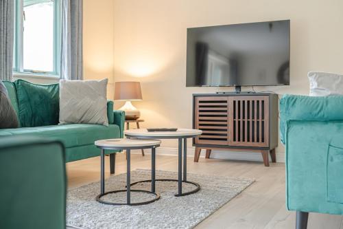 a living room with a green couch and a tv at Spacious 4 Bed 2 Bath House in Beoley