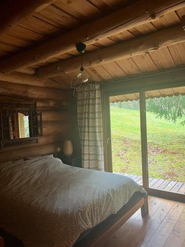a bedroom with a bed and a large window at Chalet canadien en Morvan in Rouvray