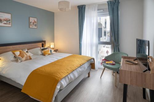 una camera da letto con un letto, una scrivania e una finestra di DOMITYS - Galia a Brive-la-Gaillarde