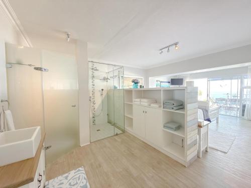 a white bathroom with a shower and a sink at Harker Street Sea Facing Studio in Plettenberg Bay