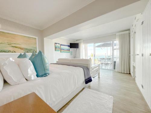 a bedroom with a large white bed with blue pillows at Harker Street Sea Facing Studio in Plettenberg Bay