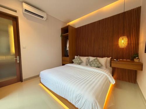 a bedroom with a white bed with a wooden wall at Genta Villa Bali in Sanur