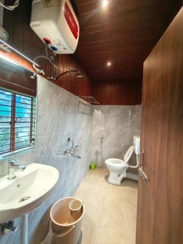 a bathroom with a white toilet and a sink at Seasonyard Homestead in Dibrugarh