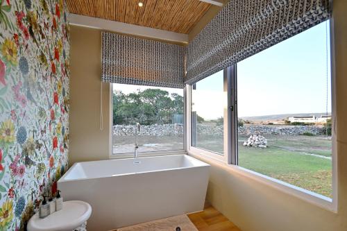 De Hoop Villa في De Hoop Nature Reserve: حمام مع حوض استحمام ونافذة كبيرة