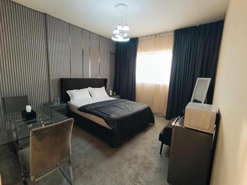 a bedroom with a bed and a desk and a window at Private Room, Inside Apartment in Ajman