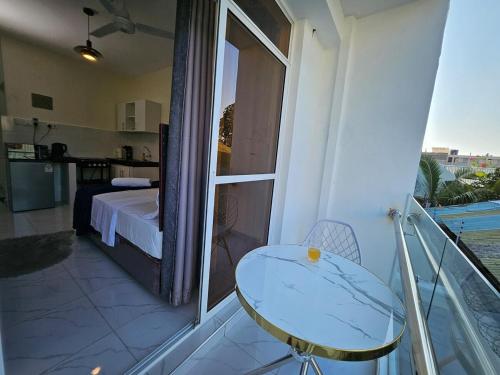 einen Balkon mit einem Bett, einem Tisch und einem Fenster in der Unterkunft Charming cosy apartment in Mtwapa