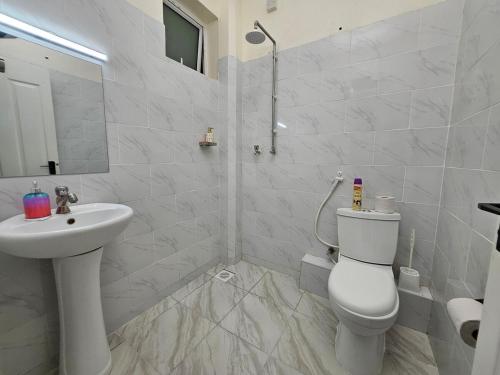 ein weißes Badezimmer mit Toilette und Waschbecken in der Unterkunft Charming cosy apartment in Mtwapa
