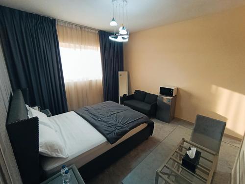 a bedroom with a bed and a couch and a chair at Private Room, Inside Apartment in Ajman