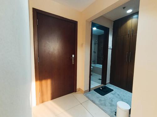 a bathroom with a wooden door and a mirror at Private Room, Inside Apartment in Ajman