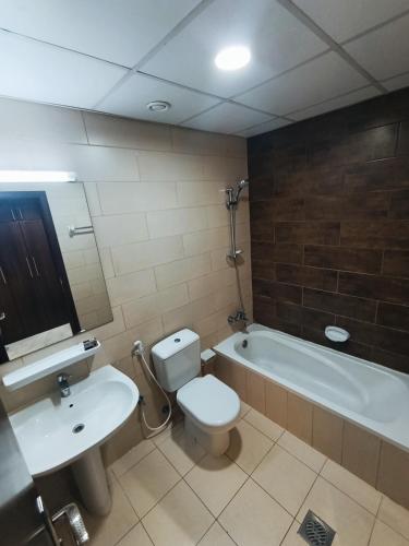 a bathroom with a toilet and a sink and a tub at Private Room, Inside Apartment in Ajman