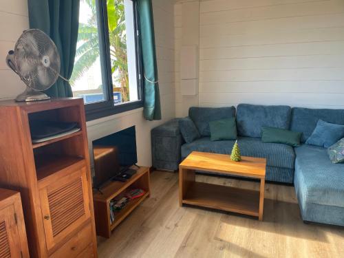 a living room with a blue couch and a table at Bungalow grand T2 saint leu in Saint-Leu
