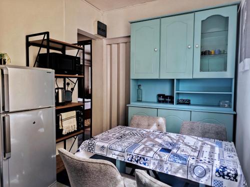 Vintage 90s Port Louis apart near Jeetoo Hospital في بورت لويس: مطبخ مع طاولة مع كراسي وثلاجة