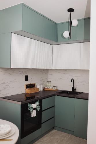 a kitchen with blue and white cabinets and a sink at Apartman Monet in Pale