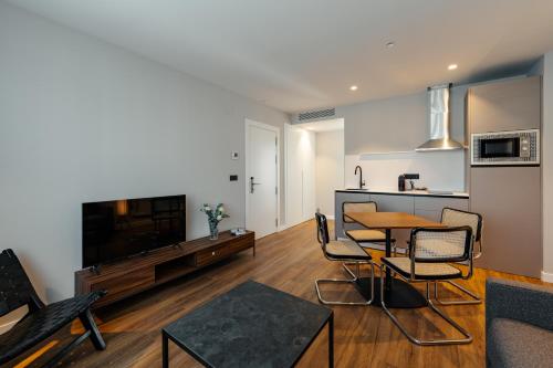 Una sala de estar con mesa de comedor y una cocina. en Apartamentos 2H LIVING, en León