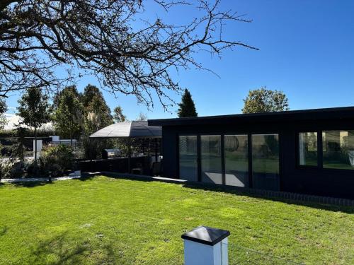 a black house with glass windows and a lawn at Little Woodlands Chalet with Private Garden & Hot Tub in Llancarvan