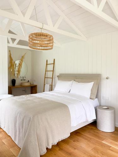 a bedroom with a large white bed and a chandelier at Ragnar Glamp Koknese Forest in Koknese